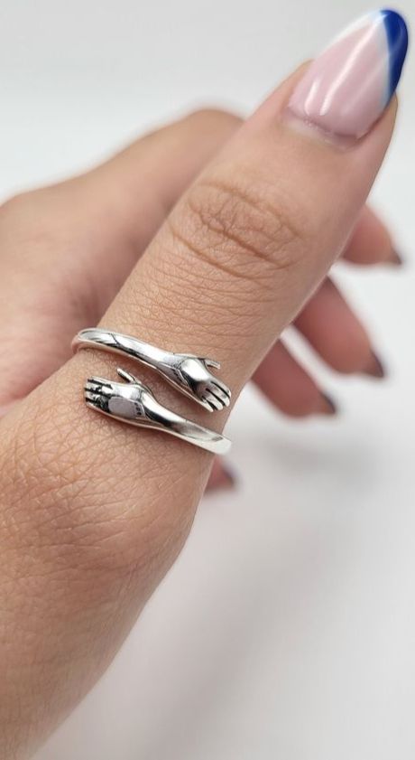 Close-up of a woman's hand wearing the silver hugging hands promise ring